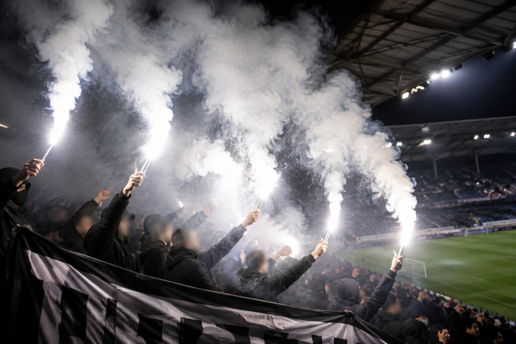 Biała flara stadionowa emitująca intensywne białe światło podczas oprawy kibicowskiej na stadionie