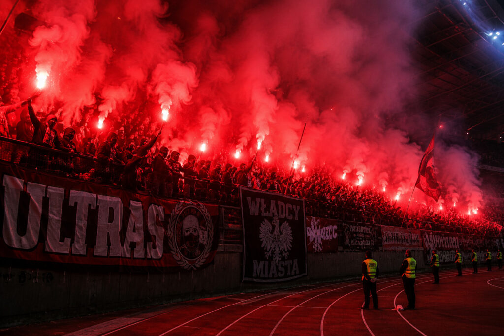 Czerwone flary stadionowe podczas oprawy kibicowskiej ultras na trybunach stadionu