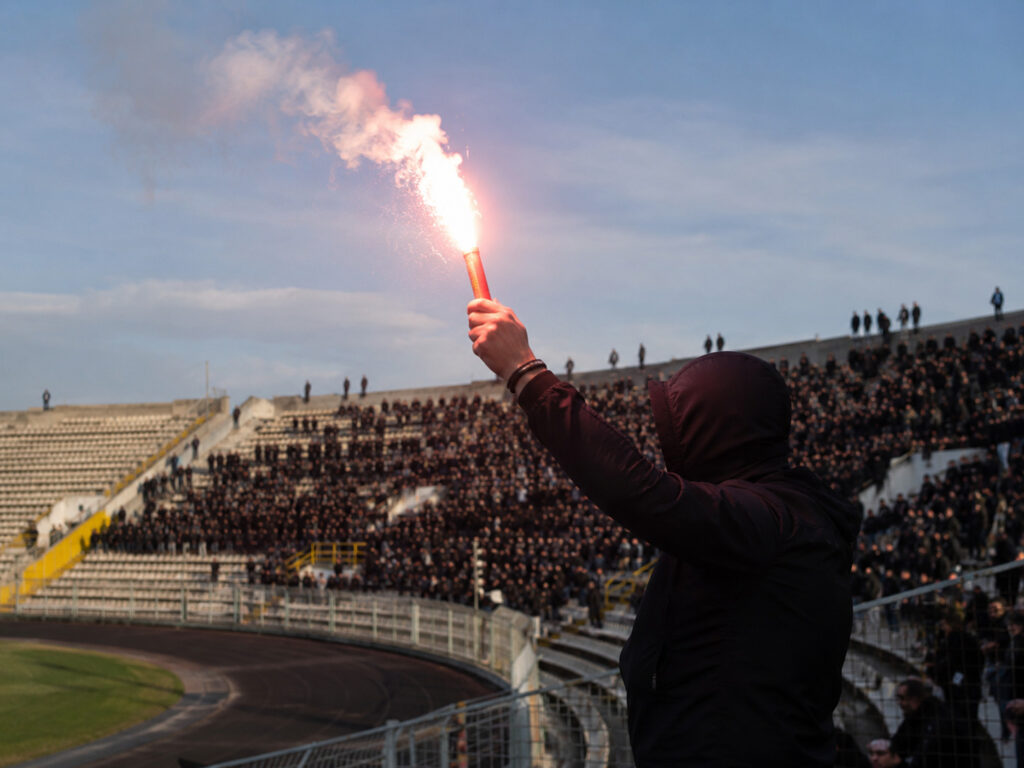 Kibic trzymający jasną racę stadionową na trybunach w ciągu dnia